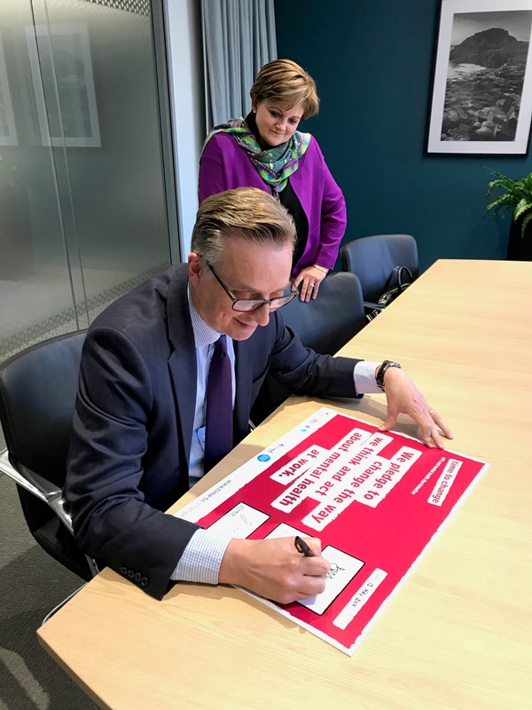 David Pollitt, writing on a red and white poster that reads: “We pledge to change the way we think and act about mental health at work