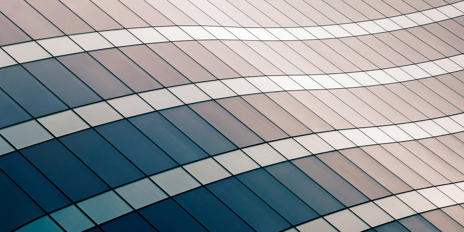 Close-up of a modern facade with wavy lines and blue and beige glass panels.