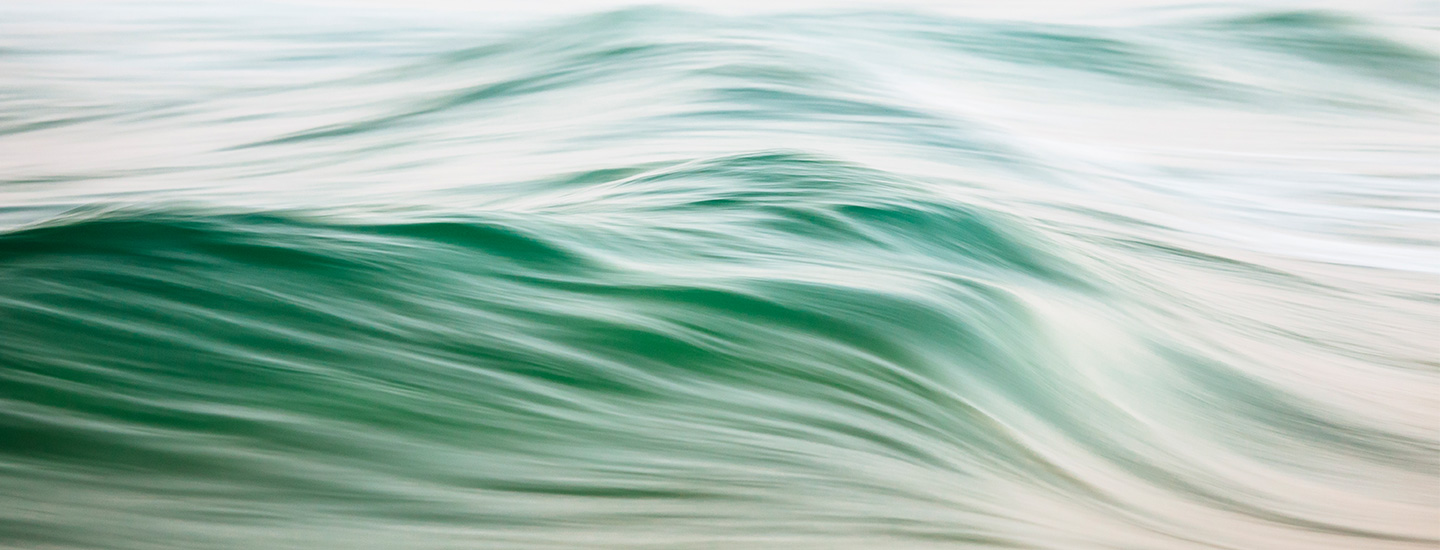 Abstract image of flowing ocean waves in blended shades of green and white.
