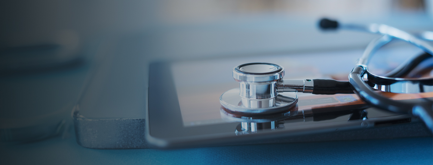 Close-up of a stethoscope resting on a tablet device with a partly blurred background.