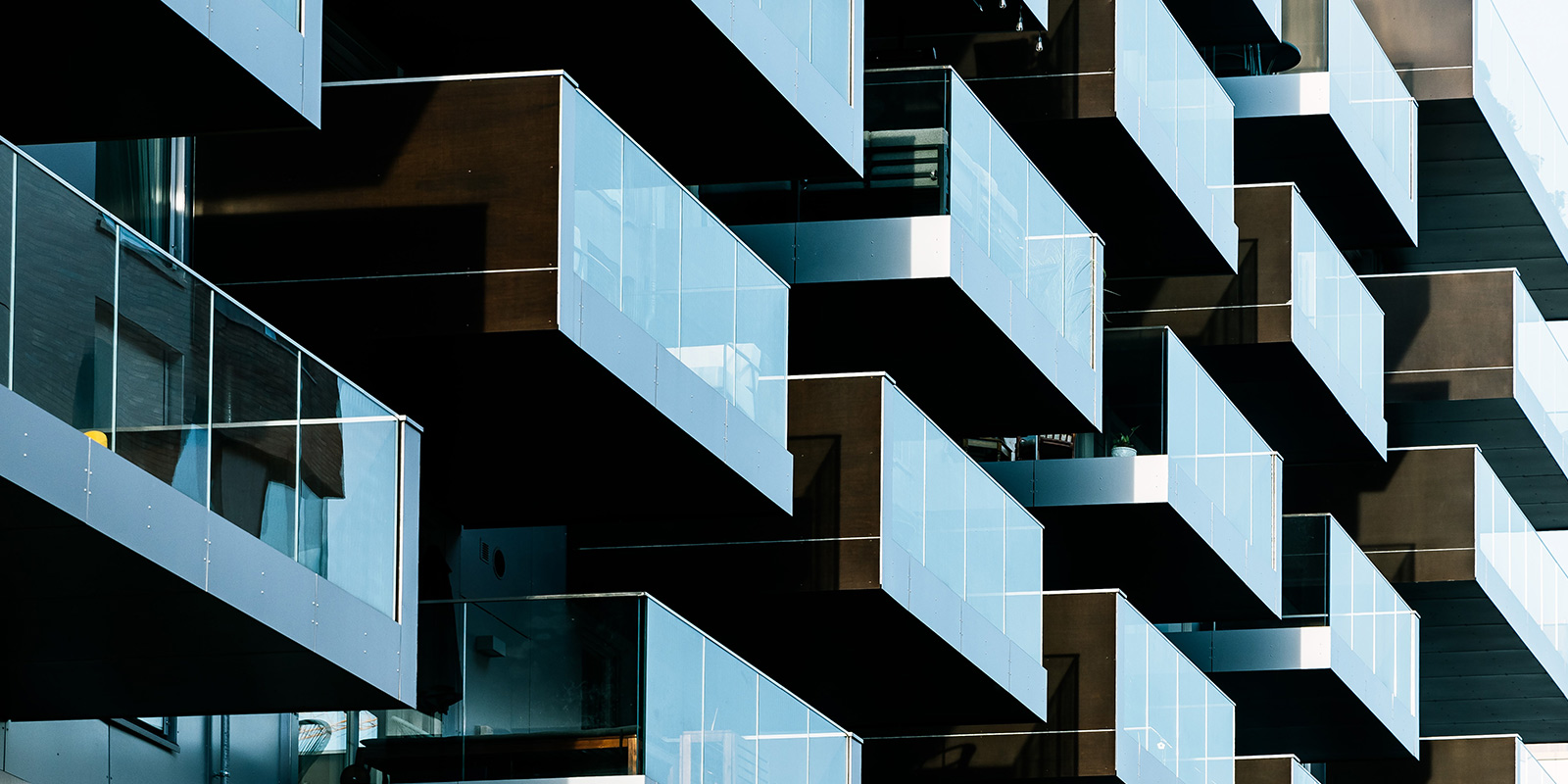 Modern building with staggered balconies and glass railings.