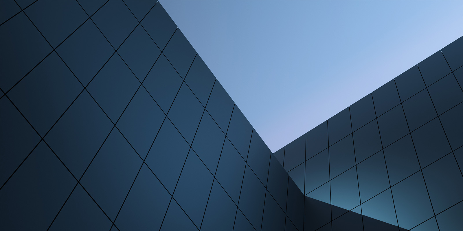 Corner of a modern building with reflective glass panels against a visible sky.