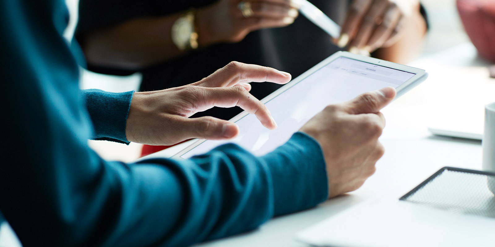 Close-up of a person using a tablet, with another individual nearby.