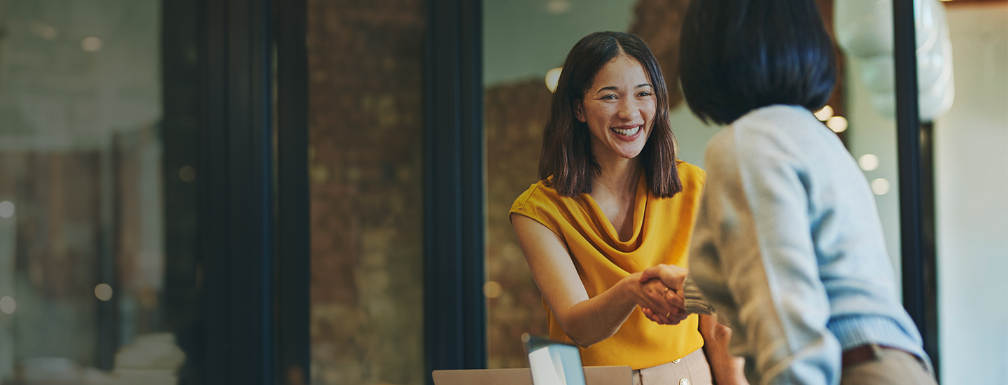 Two people shaking hands in an office setting.