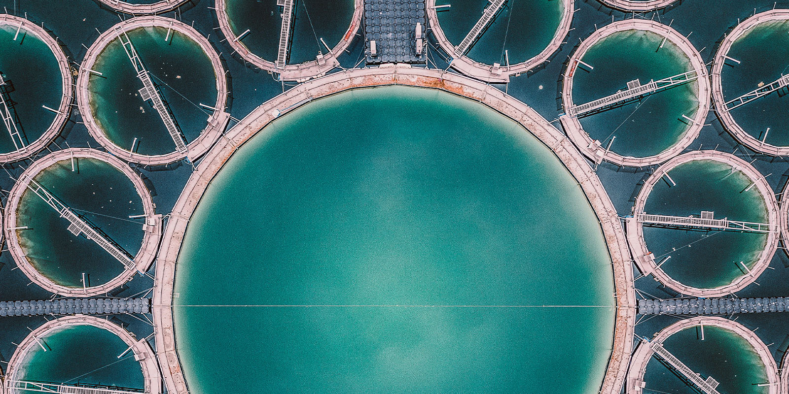 Aerial view of water treatment facility with central large tank surrounded by smaller circular tanks.