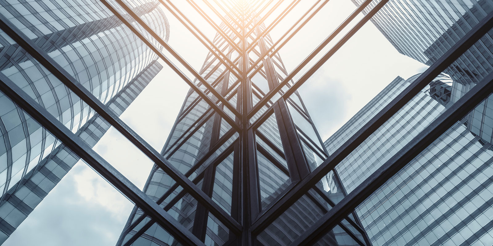 Upward view of modern skyscrapers with glass facades reflecting light and sky.