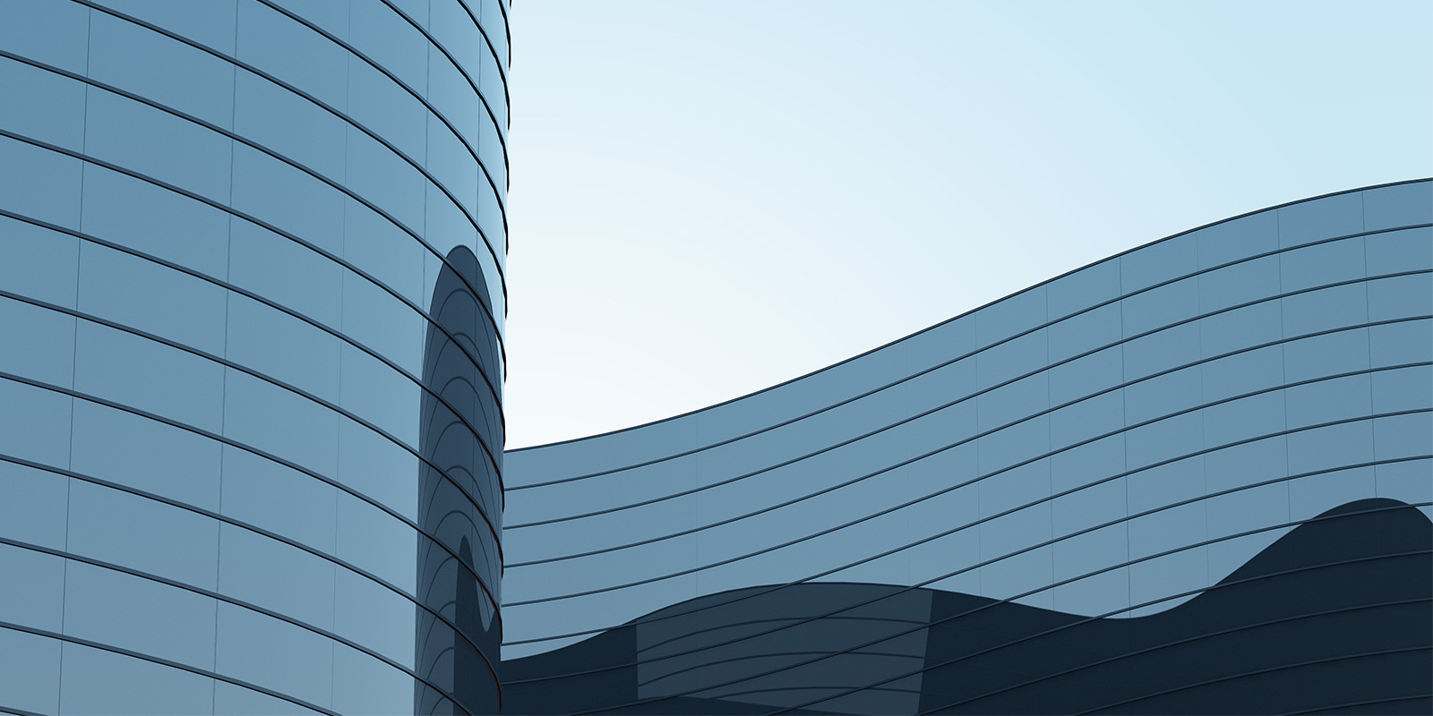 Modern building with curved reflective glass and horizontal lines against a clear sky.