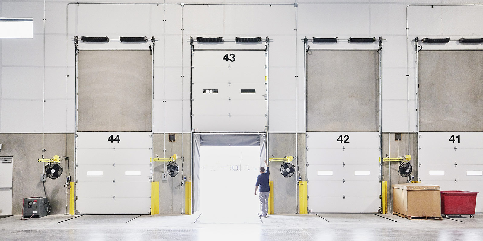 Warehouse loading dock with four doors, a person standing near the open door 43.