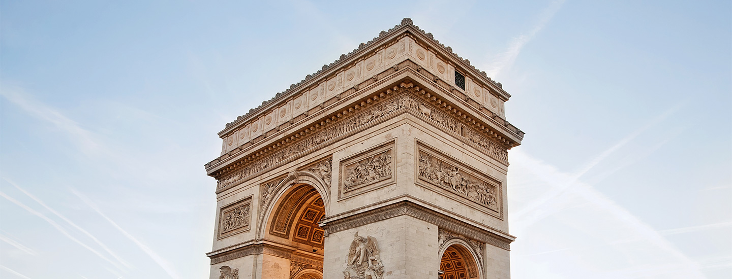 Arc de Triomphe in Paris with clear sky and airplane contrails.