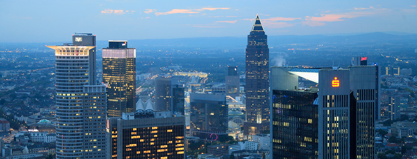 Frankfurt skyline at dusk with lit skyscrapers and fading sky.