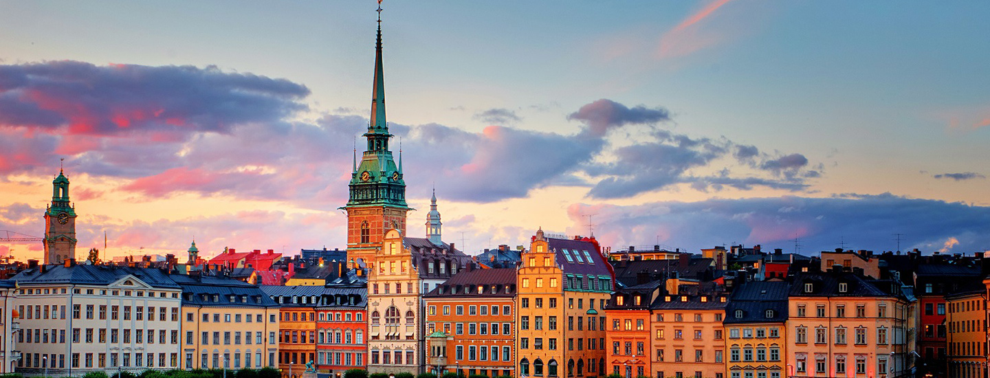 Gamla Stan in Stockholm at sunset with colorful buildings and church spire.