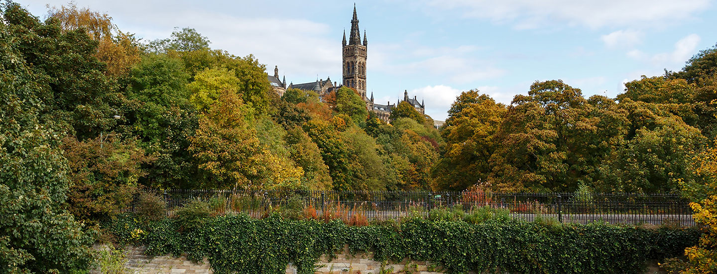 Old clock tower in Scotland with autumn trees and ivy-covered wall.