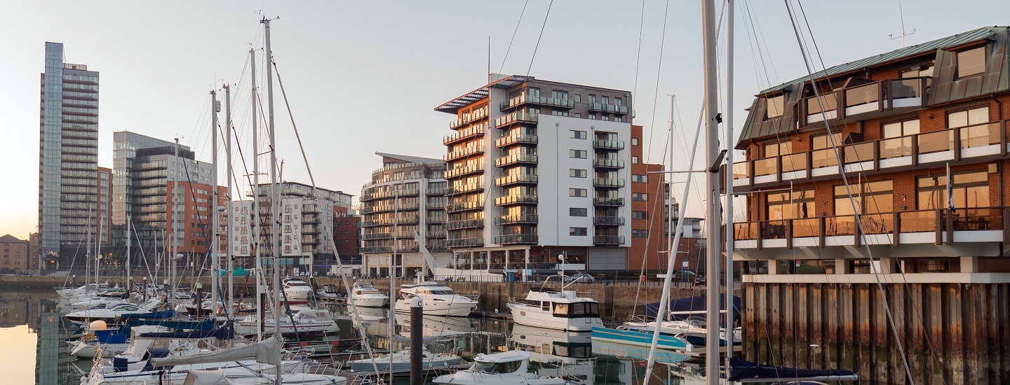 Southampton marina with docked boats and modern high-rise buildings under clear skies.