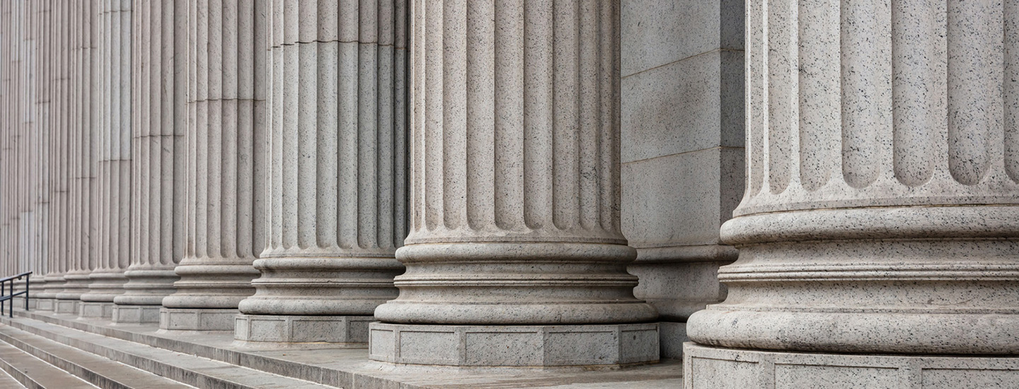 Row of large fluted stone columns with bases resting on steps leading up to a classical-style building